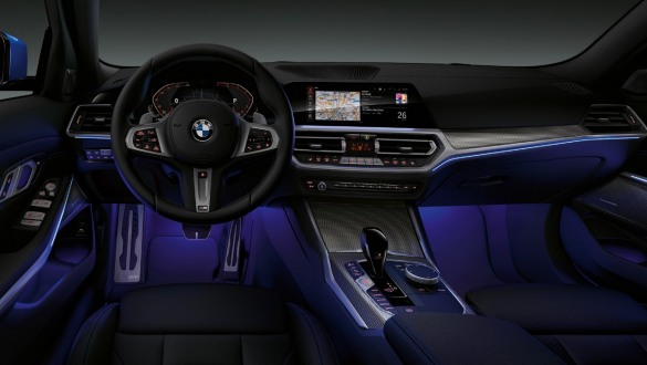BMW 3 Series Sedan, Ambient light. Front view of the driver's cockpit of the BMW 3 Series Sedan with by Ambient light blue illuminated legroom.