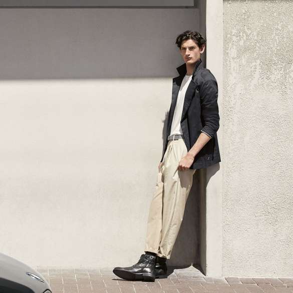 BMW i Collection. The picture shows a man leaning against a wall in a BMW i Jacket, Men from the BMW i Collection.
