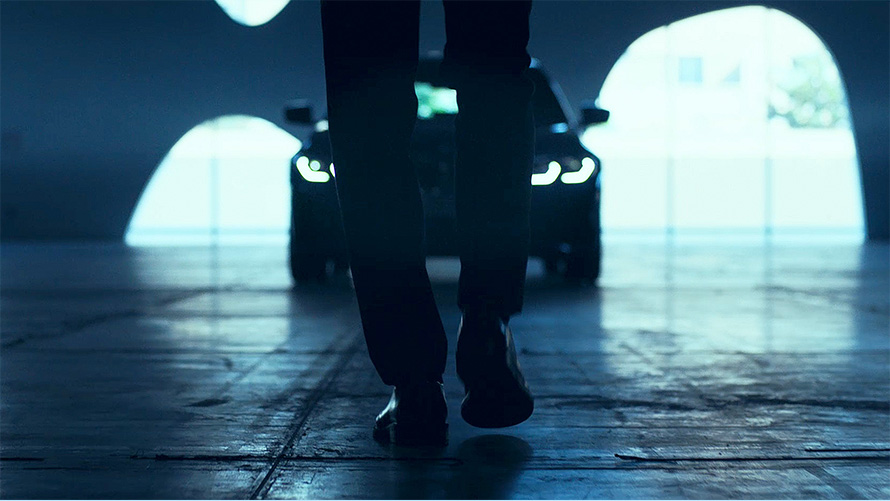 BMW 3 Series Sedan (G20), Front. View from behind of walking man in front of the BMW 3 Series Sedan (G20) on asphalt.