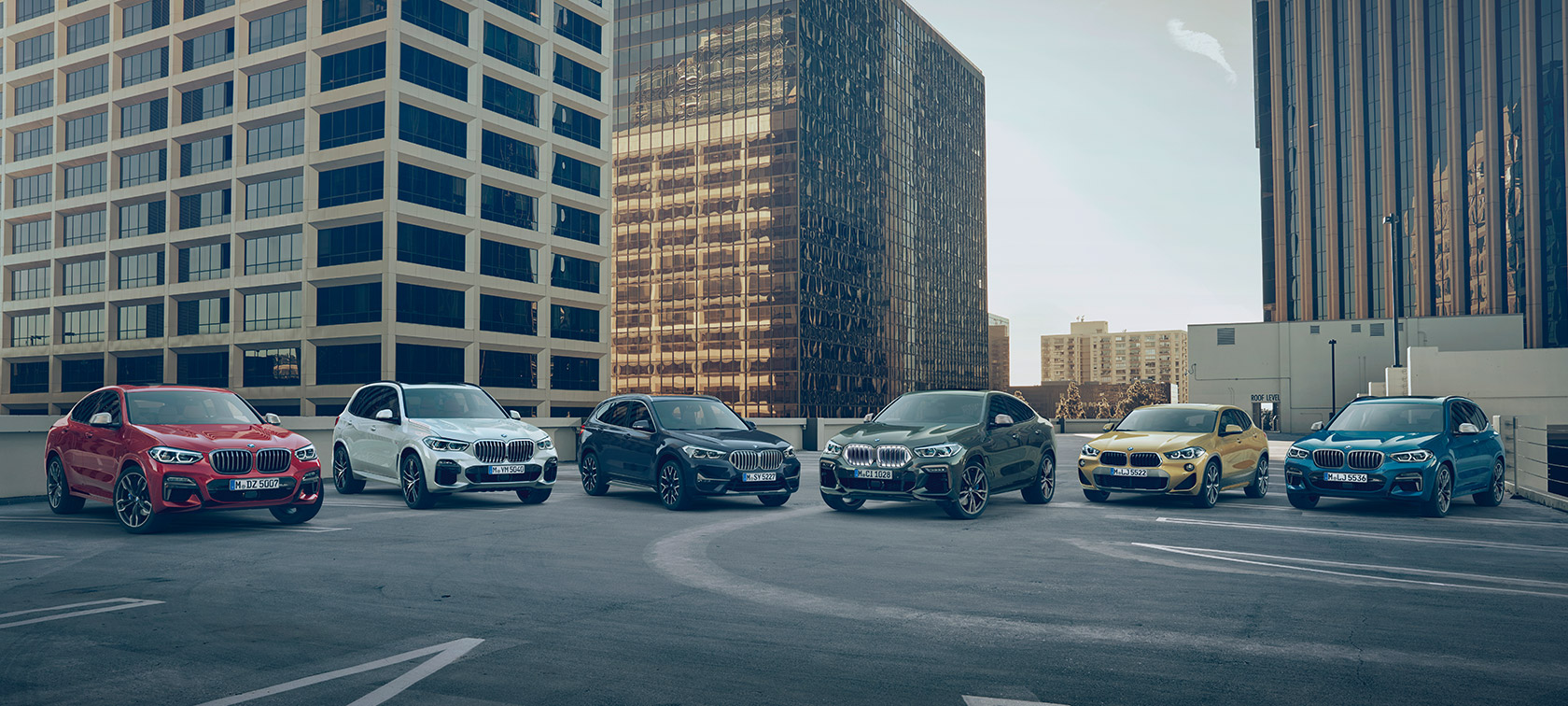 BMW X vehicles on parking deck in front of buildings BMW X Series BMW X vehicles on parking deck in front of buildings