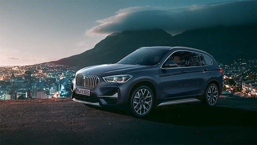 BMW X1 F48 LCI three-quarter side view standing in front of urban scenery
