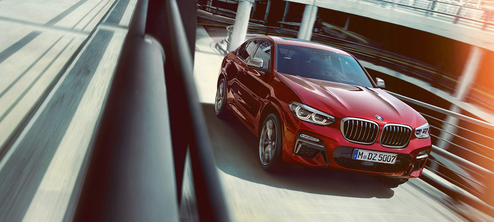 BMW X4 driving in the multi-storey car park BMW X4 G02 2018 Flamenco Red brilliant effect three-quarter side view driving in the multi-storey car park