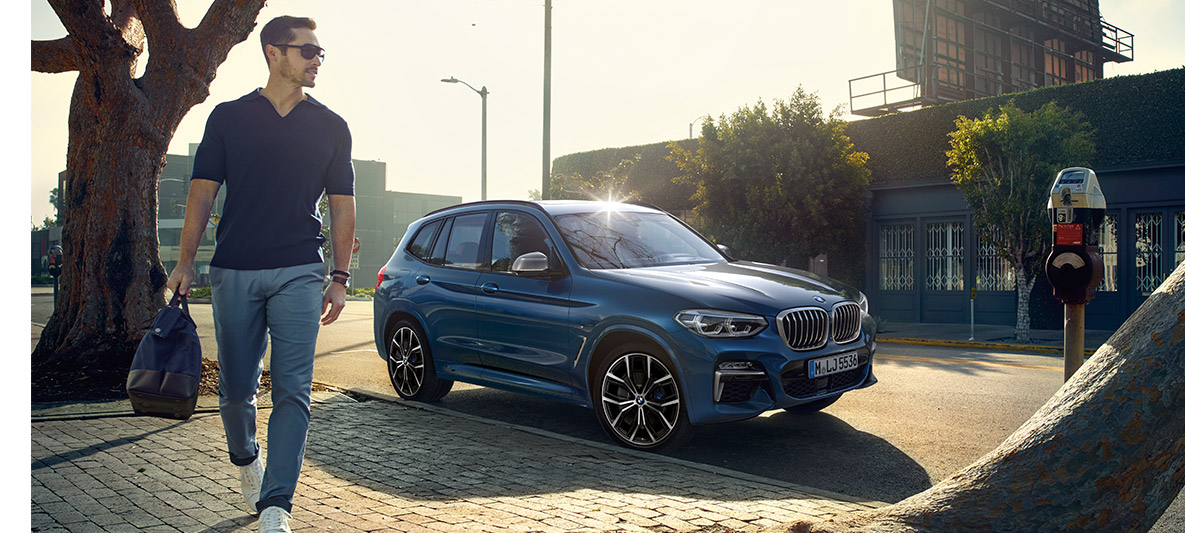 Man with sunglasses in front of blue BMW Man with sunglasses in front of blue BMW