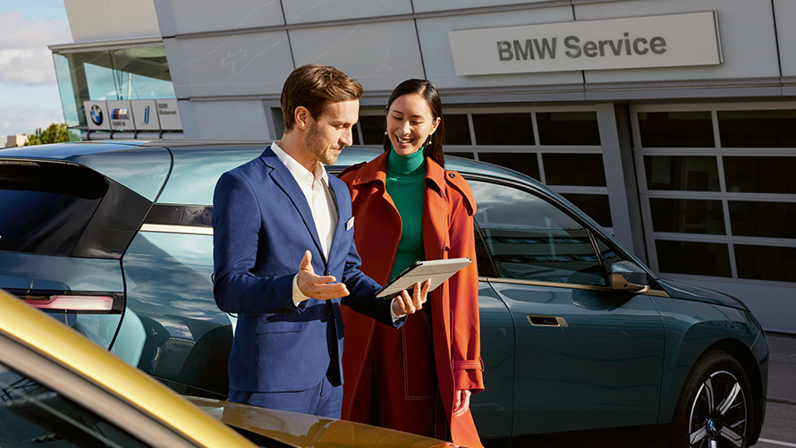 BMW Service man and woman in front of BMW iX at BMW service partner 