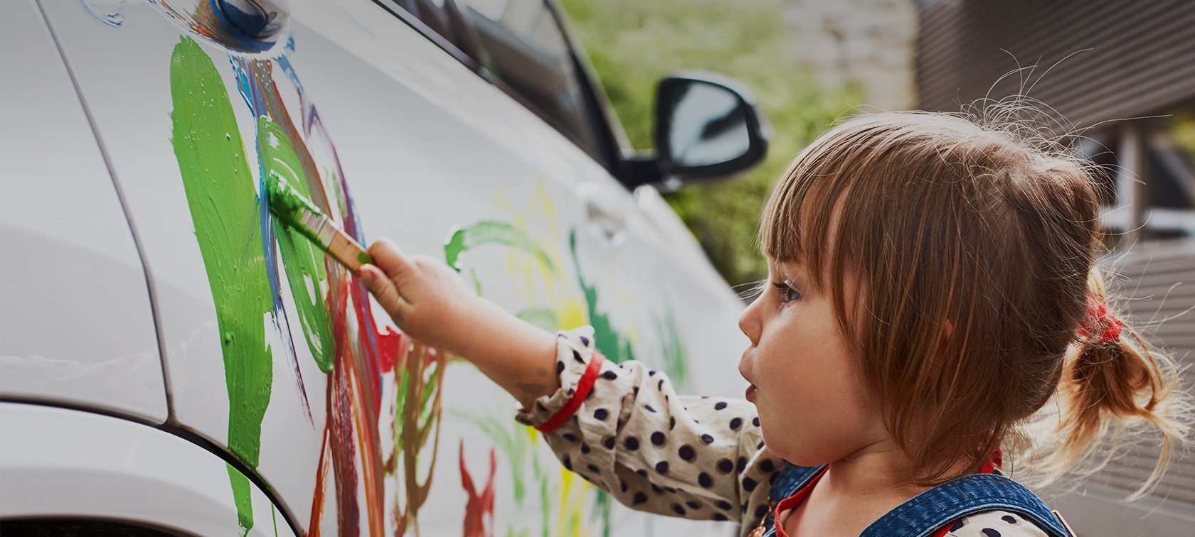 A little girl is painting a white BMW with colour. A little girl is painting a white BMW with colour.